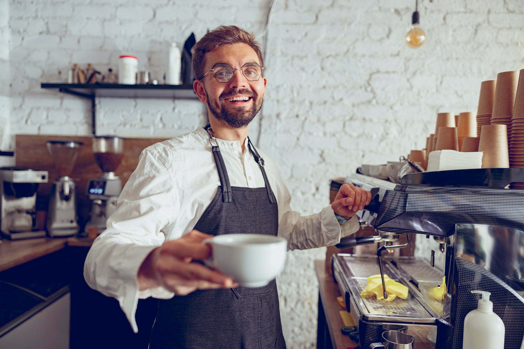 Cheerful male barista offering coffee in cafe Cheerful male barista offering coffee in cafe