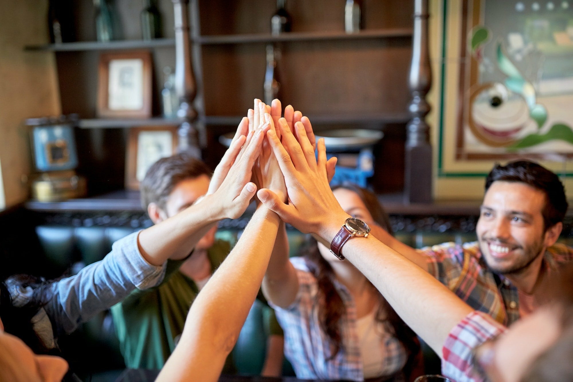 happy friends making high five at bar