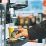 Young man driver pours coffee to go in the store at the gas station