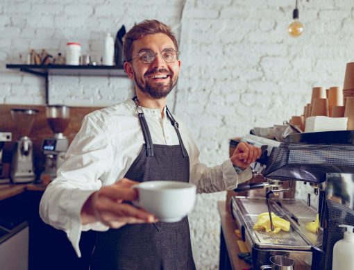 Cheerful male barista offering coffee in cafe